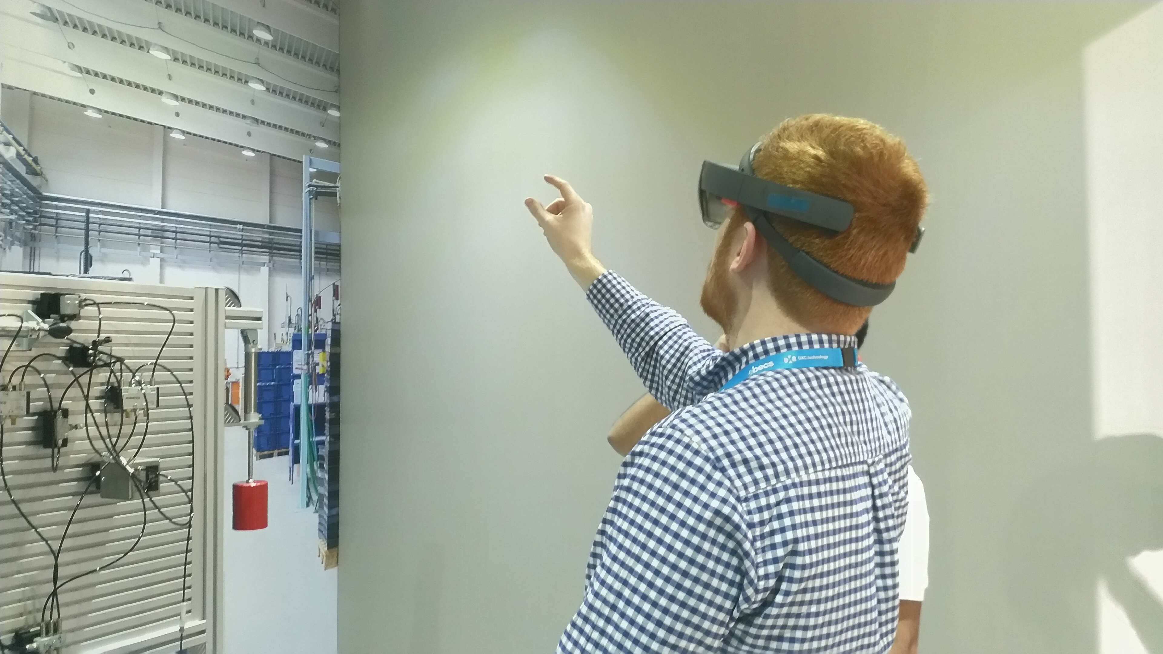 Matthew Champion wearing a HoloLens. He is reaching into the air with his index finger and thumb pinching in the air.
